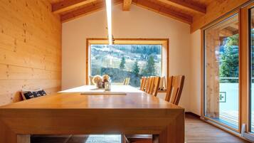 A dining area with a wooden table, chairs, and a large window with a view of a mountainous landscape.