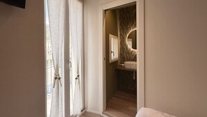 Un dormitorio con un ventanal grande, una puerta que da al baño y una cama.
