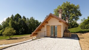 Pieni, yhden kerroksen rakennus, jossa on kalteva katto, puinen ulkoverhous ja savupiippu.
