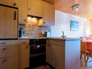 Eine Küche mit Holzausstattung, einem eingebauten Backofen, einer Kaffeemaschine und einer gefliesten Spritzschutzwand.