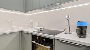 Une cuisine moderne équipée d’un four encastré, d’une machine à café et d’un évier.