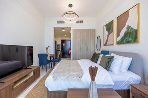 Quarto de hotel moderno com uma cama, mesas de cabeceira, televisão e obras de arte nas paredes.