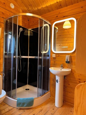 Een douche, handdoeken, zeep, toiletpapier