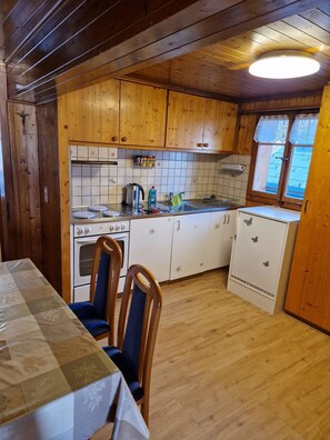 Una cucina con mobili in legno, un fornello, un lavello e un frigorifero.