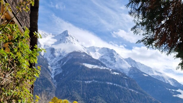 Ein Tisch mit einem gelben Blumentopf, Blick auf die Berge und ein Holzzaun.