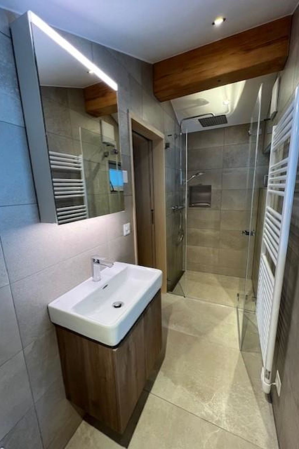 Ein modernes Badezimmer mit integriertem Waschbecken, einer Duschkabine aus Glas und einem sichtbaren Handtuchhalter.