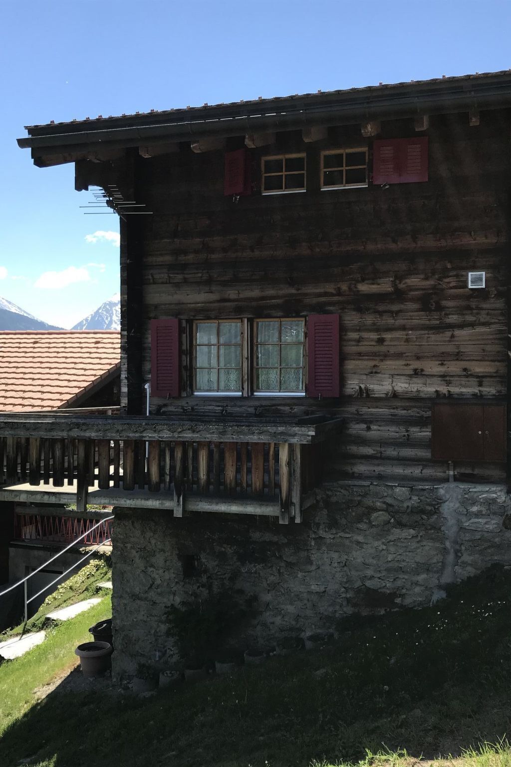 Ein rustikales Holzhaus mit Balkon, Stein Fundament und Bergblick.