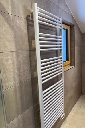 Een witte radiator aan een muur, met een raam ernaast.