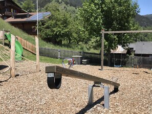 A playground with a seesaw, a slide, and a swing set. - Stubulti Appartement/Fewo, Dusche und Bad, WC 3 1/2 Zimmerwohnung, 4-Betten by Interhome (Riederalp)