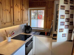 Una cocina con armarios de madera, una cafetera, un lavabo y un refrigerador con imanes.