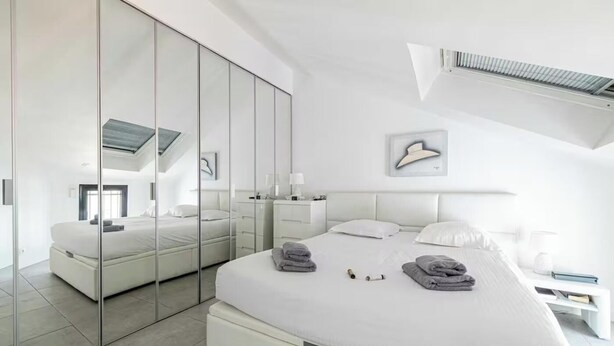 Une chambre moderne avec un grand lit, un dressing et un ventilateur de plafond.