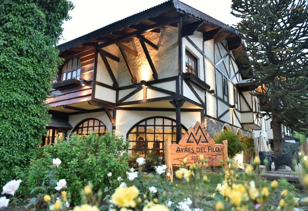 Een chaletachtige woning in traditionele stijl, met een bord waarop 'AYRES DEL FILO SUITES' staat.