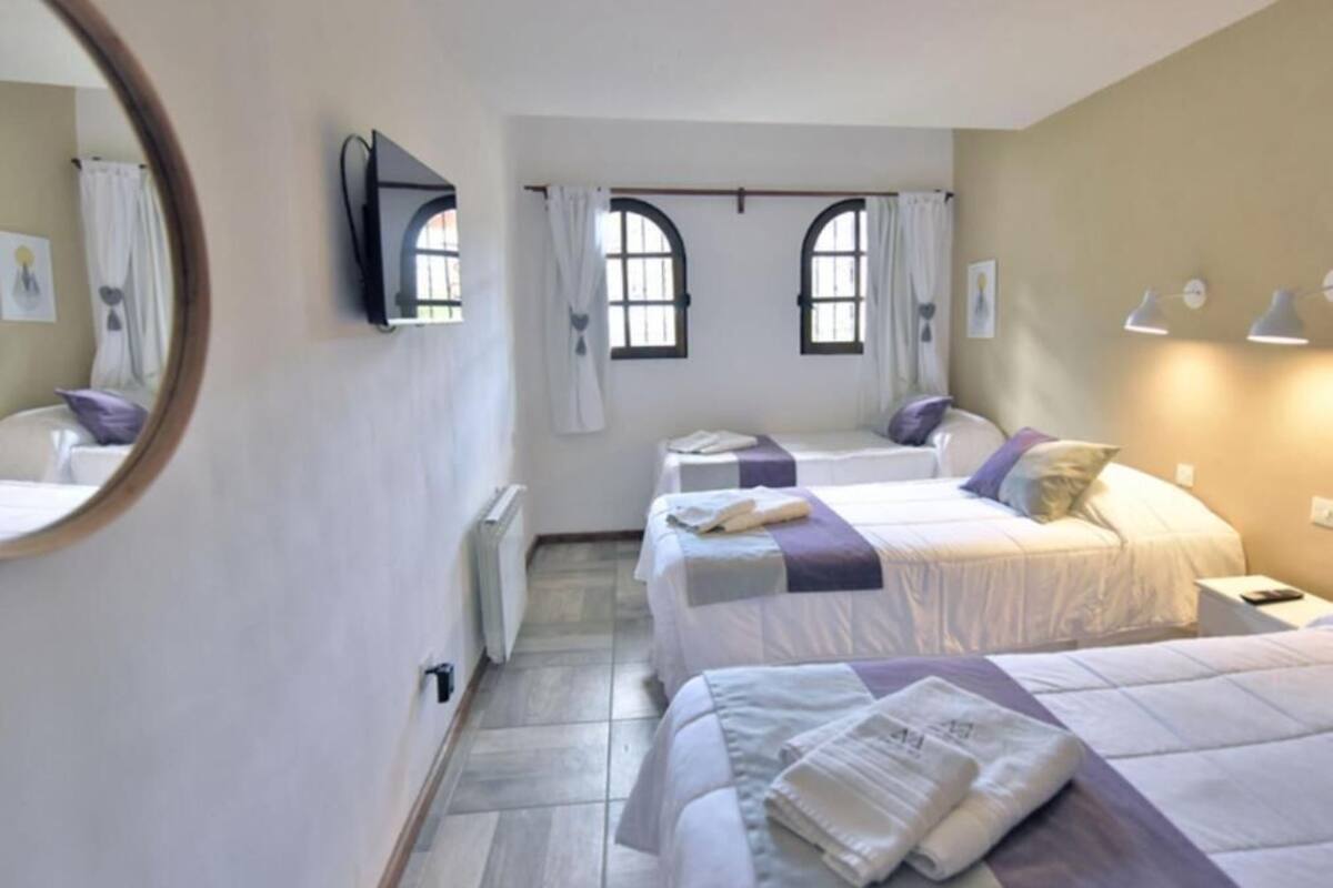 Een slaapkamer met twee bedden, een spiegel en twee ramen met gordijnen.
