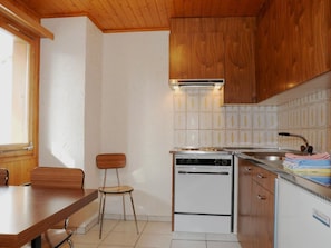 A compact kitchen with wooden cabinets, a stove, and a sink.