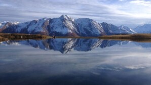 Un lac paisible dont les eaux reflètent clairement les montagnes enneigées.
