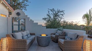 An outdoor seating area with wicker furniture, a central fire pit, and decorative lighting. - MT Views, Golf Oasis, Htd POOL, Spa, Smart TVs (Gold Canyon)