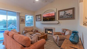 A living room with a fireplace, sofas, a coffee table, and a TV. - MT Views, Golf Oasis, Htd POOL, Spa, Smart TVs (Gold Canyon)