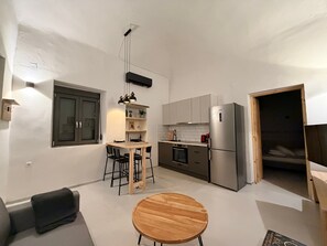 Una cocina funcional con comedor, refrigerador y una pequeña zona de estar.