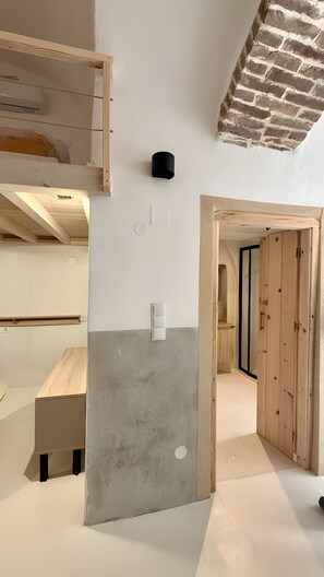 Una habitación con ladrillo visto, una puerta de madera y un interruptor de luz en la pared.