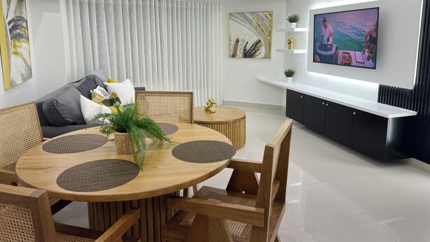 Una sala de estar moderna con una mesa de comedor redonda, sofás, un televisor y un aire acondicionado.