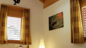 Habitación de hotel con cama, un cuadro, adorno de gallo y cortinas.