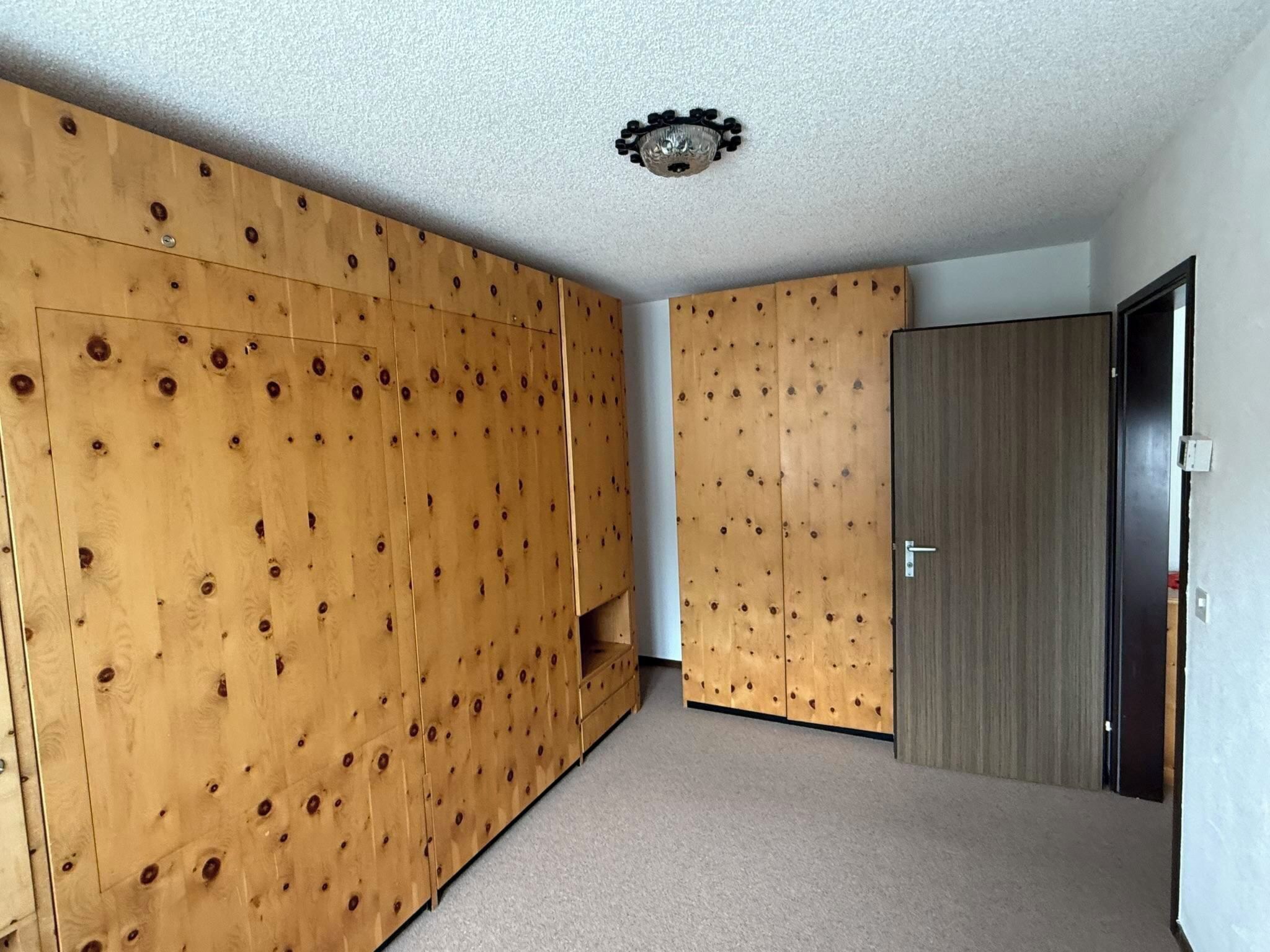 Ein Zimmer mit Holzvertäfelung, Teppichboden und einer Tür.