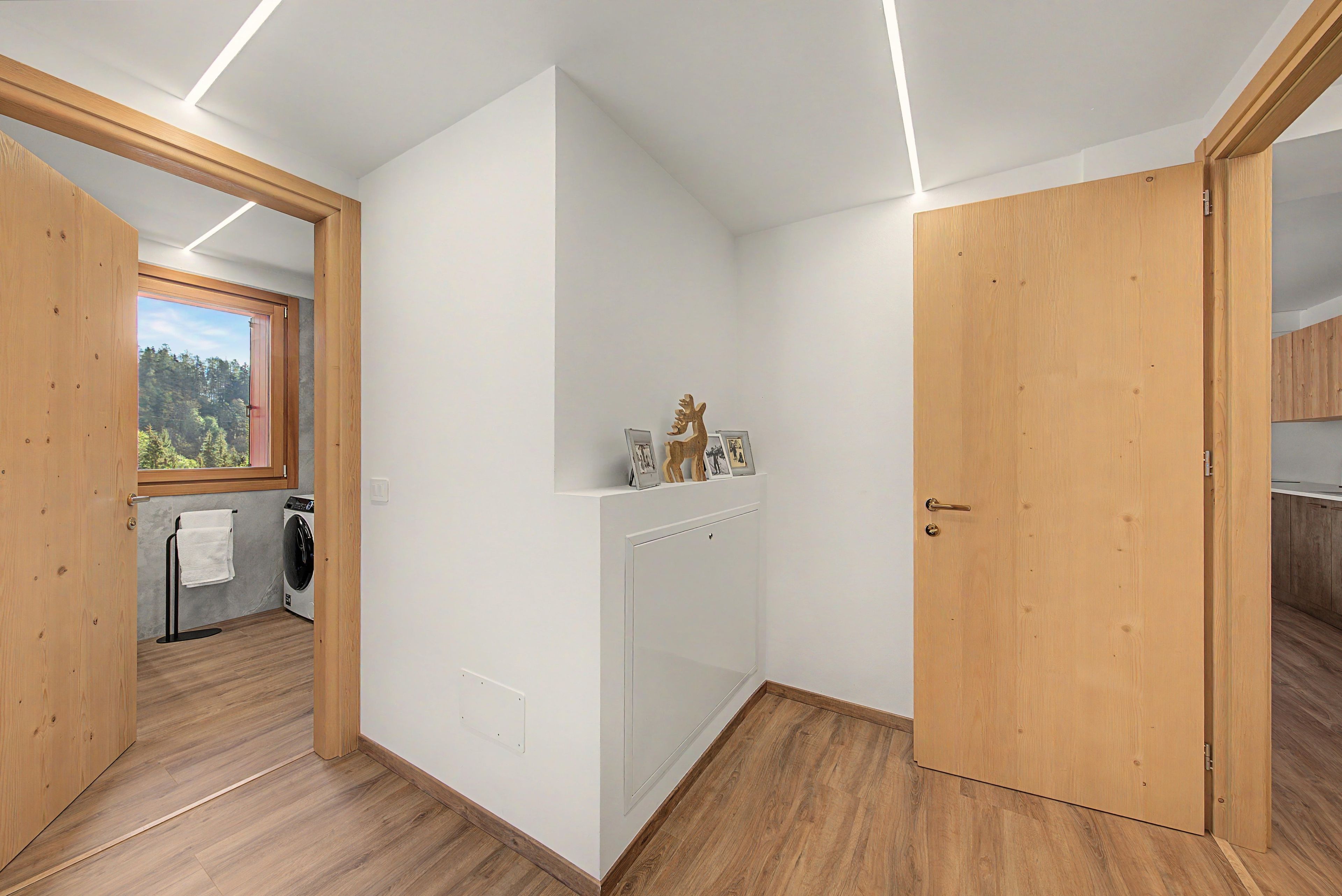 Ein modernes Interieur mit Waschbereich, Holzböden und Blick durch ein Fenster.