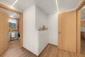 A modern interior with a laundry area, wooden flooring, and a view through a window.