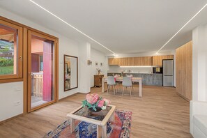 A modern kitchen with wooden cabinets, a dining area with a table and chairs, and a living space with a sofa and a coffee table.