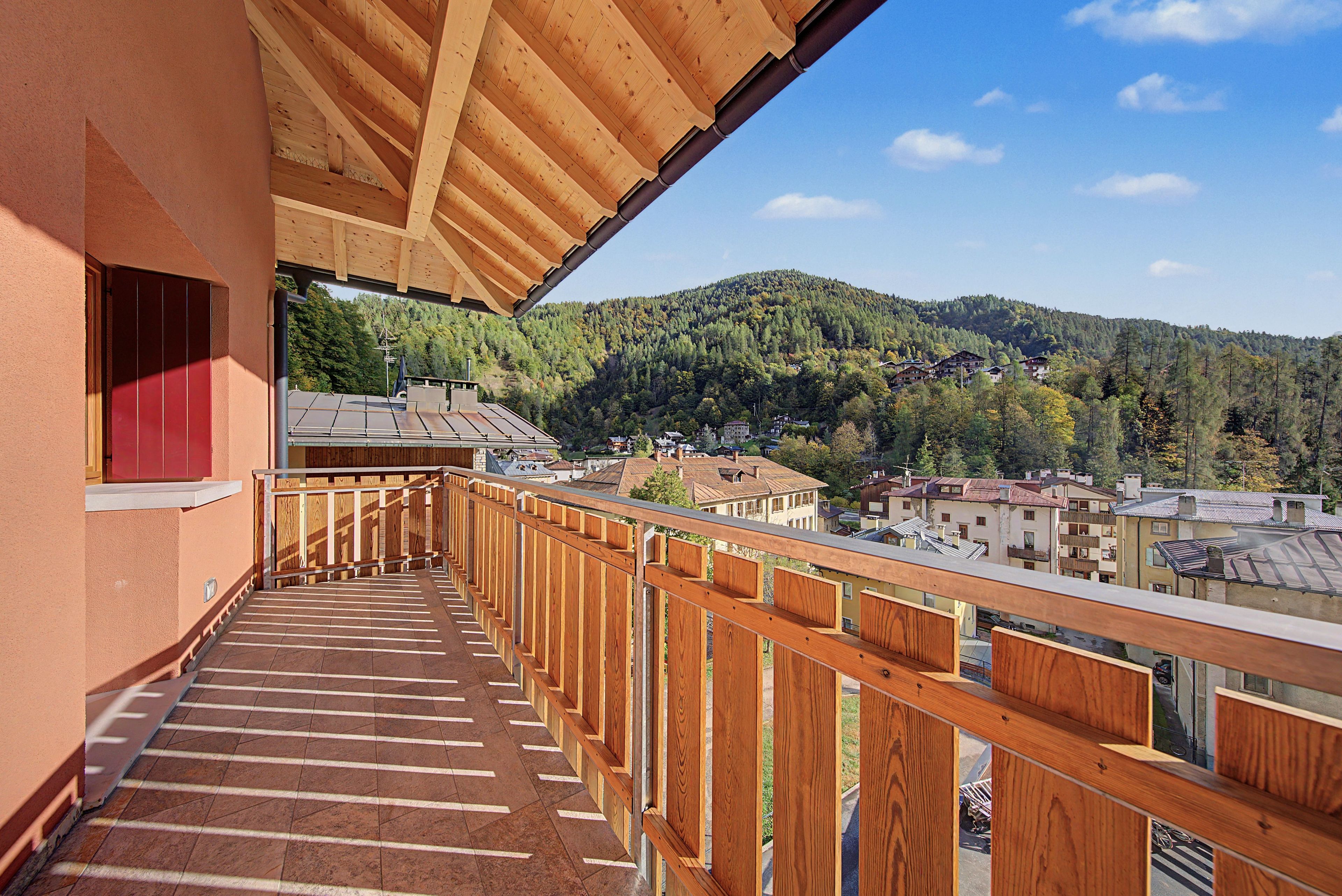A wooden balcony with a view of a hillside village.