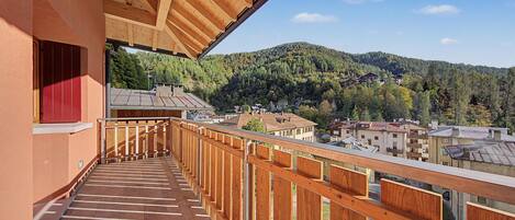 A wooden balcony with a view of a hillside village.