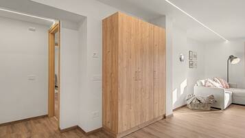 Una habitación moderna con un armario de madera, un sofá blanco y una lámpara de pie.
