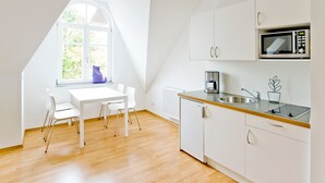 A modern kitchen with white cabinets, a microwave, a coffee maker, and a window with a view of greenery. - Stadt Land Fluss Studio Apartment '2' in Regensburg (Regensburg)