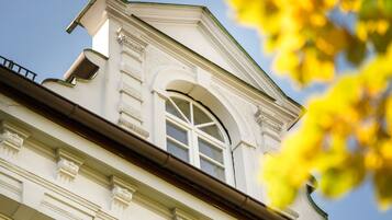 En byggnad i klassisk arkitektonisk stil, med ett framträdande, välvt fönster och dekorativa lister.