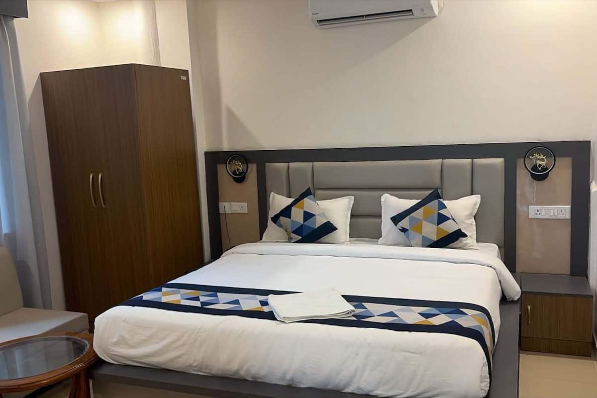 A hotel room with a bed, a wardrobe, a bedside table, and a small round table.