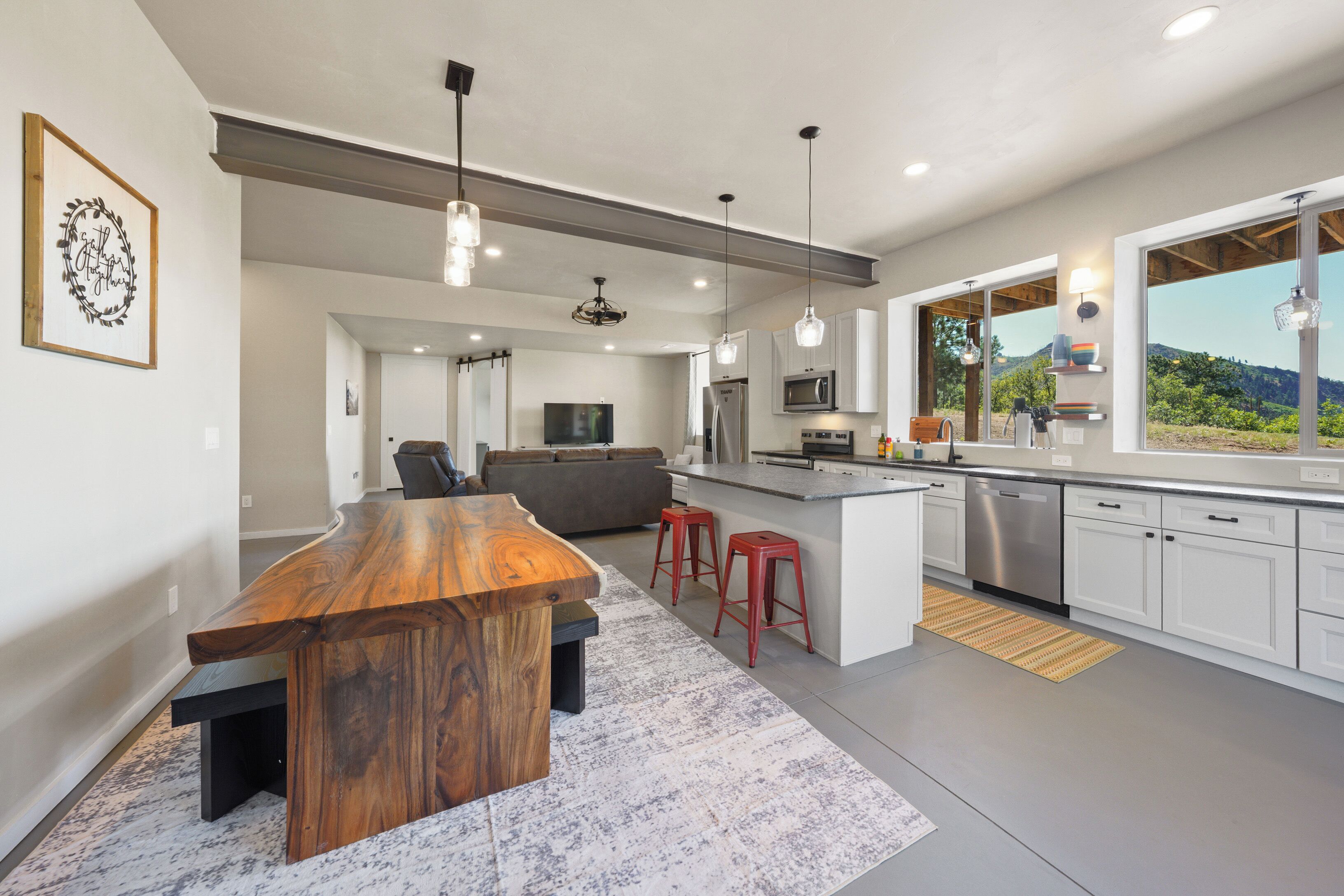 A modern kitchen with a wooden island, bar stools, a built-in oven, and a large window with a view.