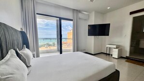 Una habitació d'hotel amb un llit gran, una televisió i vista a l'oceà.