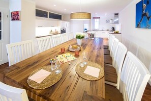 Un comedor con una mesa de madera, sillas blancas y un tablero de ajedrez.