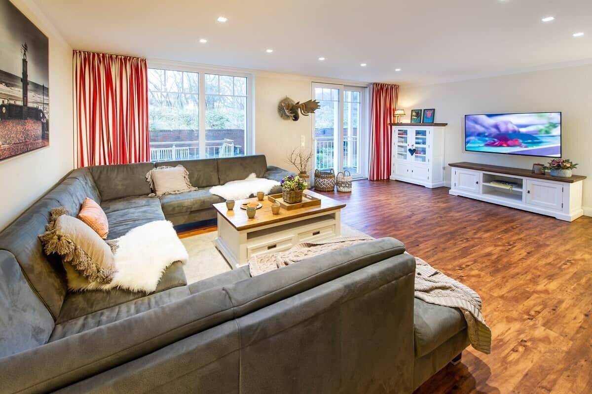 A modern living room with a grey sofa, a coffee table, a TV, and a white cabinet.