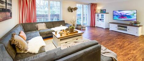 A modern living room with a grey sofa, a coffee table, a TV, and a white cabinet.