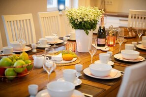 A dining table set with white dishes, glasses, and a bottle of wine.