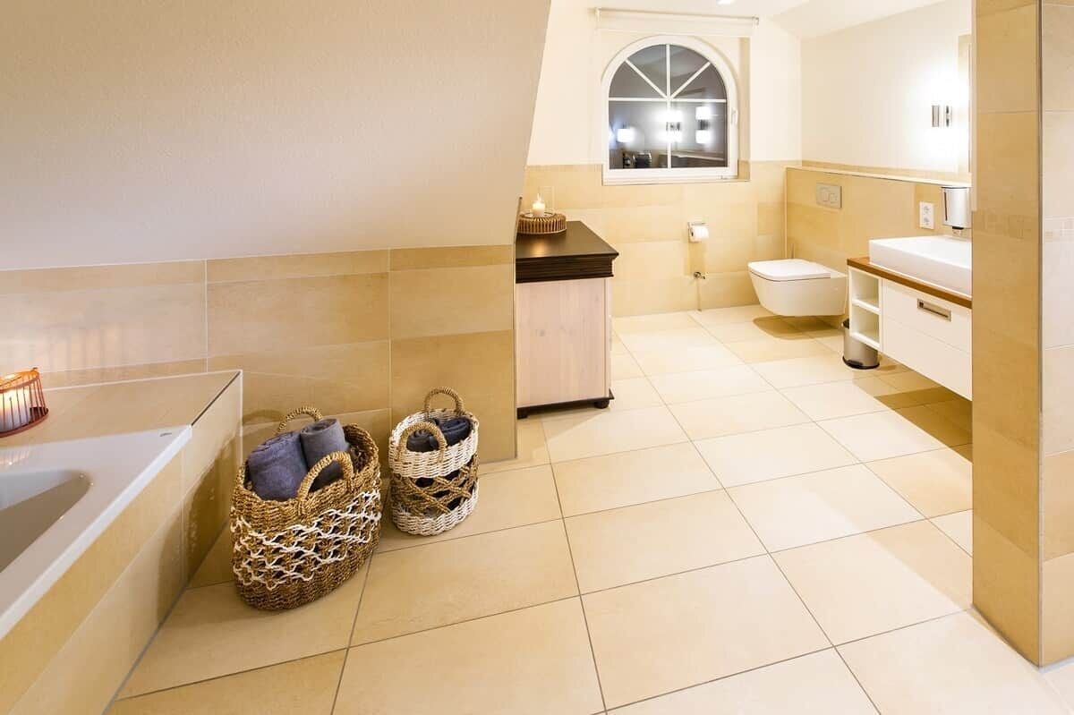 Une salle de bain moderne avec une baignoire, des toilettes et un meuble-lavabo. On y trouve des paniers en osier sur le sol et une fenêtre avec vue.