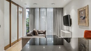 A modern living room with a sofa, a flat-screen TV, and a glass coffee table. - Riverside Studio Manhattan Sleeps 2 - Chelsea AC (London)