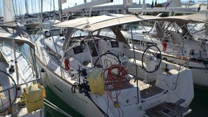 Un barco llamado 'Hana' atracado en un puerto deportivo junto a otras embarcaciones, con una zona de estar cubierta y varios equipos.