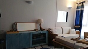 Ein Wohnzimmer mit einer Couch, einem blauen Schrank, einer Lampe und einem gemusterten Boden.