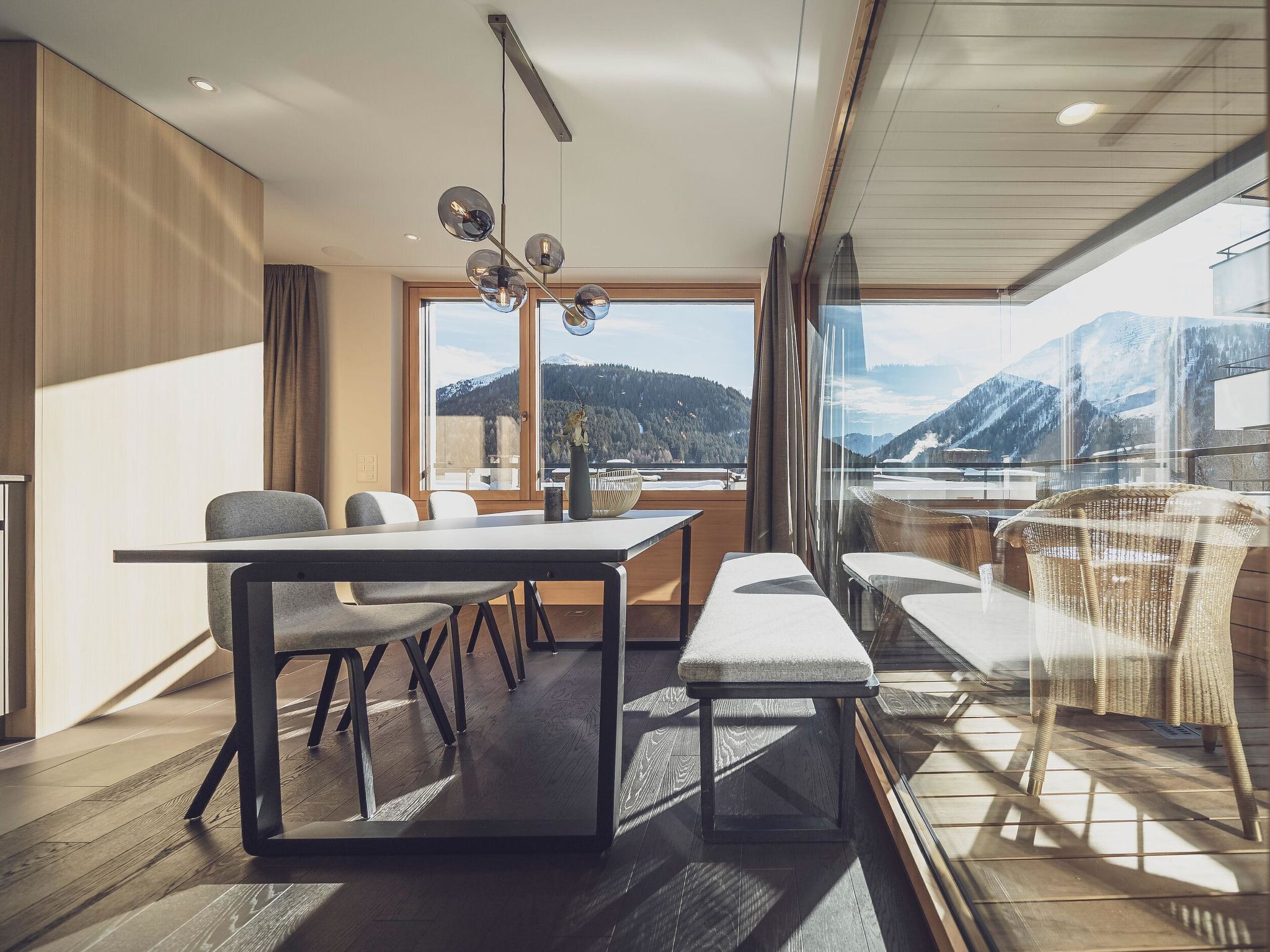 Ein modernes Interieur mit Essbereich, großen Fenstern und Bergblick.