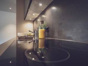 Eine moderne Küche mit glänzender Arbeitsplatte, einer Schüssel, einer Flasche und einer Pflanze.