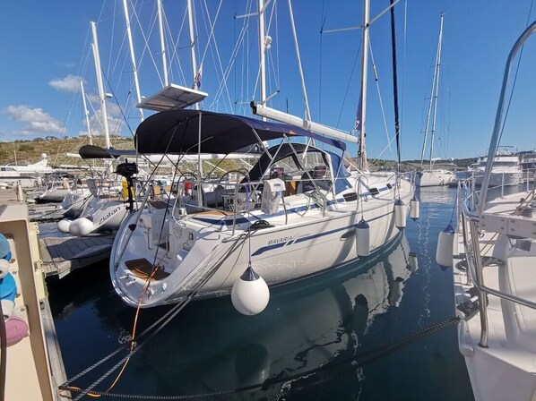 A marina with multiple sailboats docked, featuring masts, sails, and a covered area. - Sun-Kissed Sailing Adventure in Sibenik, Croatia (Primošten)