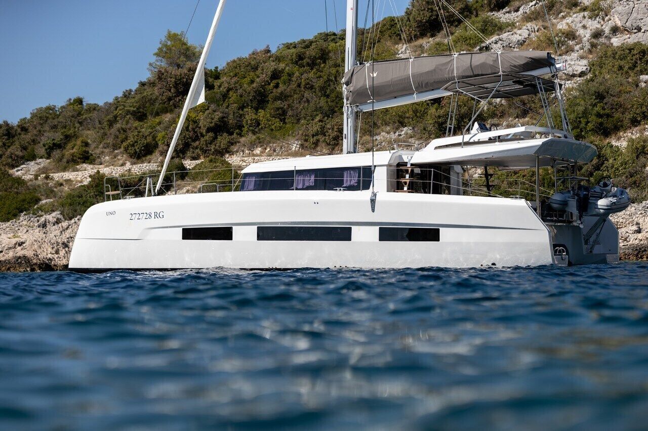 A white yacht with a cabin, sails, and a covered area.