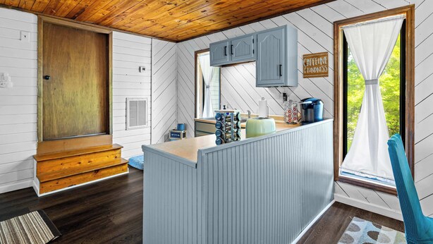 A kitchen with wooden ceiling, a central island, and a window with a view.